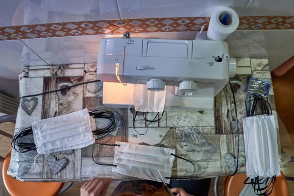 Woman's hands sewing cloth masks at home with a sewing machine to protect from the coronavirus.