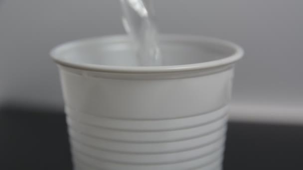 Water pouring down into plastic cup — Stock Video