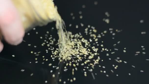 Рука льет коричневый сахар на черную поверхность — стоковое видео