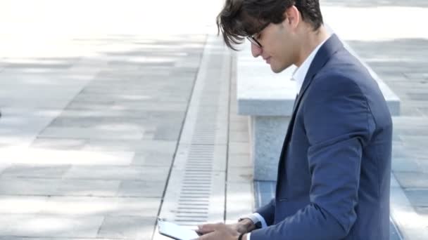 Knappe jongeman werken bij tabletcomputer buiten — Stockvideo