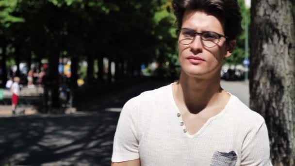 Стильний молодий чоловік, що стоїть в міському парку — стокове відео