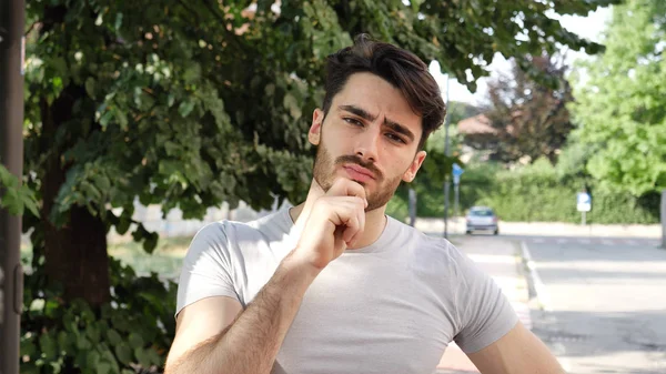 Confuso giovane uomo grattandosi la testa, alzando lo sguardo — Foto Stock