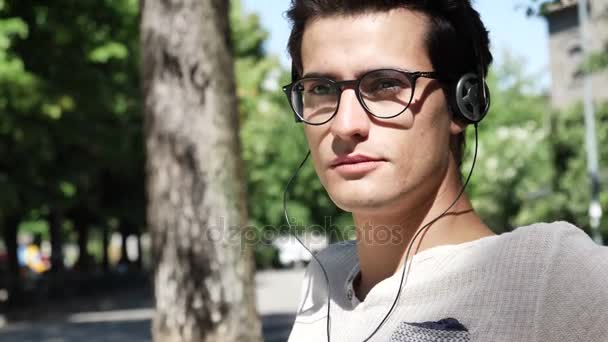 Молодий чоловік слухає музику в парку — стокове відео