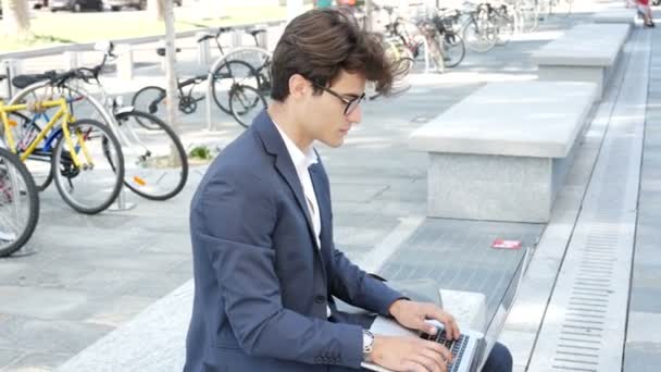 Guapo joven trabajando en la computadora al aire libre — Vídeo de stock