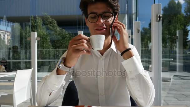 Joven bebiendo café y hablando por teléfono — Vídeos de Stock