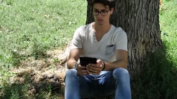 Jeune homme dans le parc de la ville en utilisant ebook reader — Video