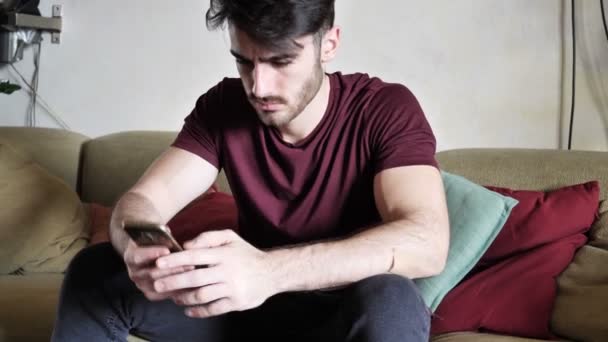 Привлекательный молодой человек делает покупки онлайн на мобильном телефоне — стоковое видео