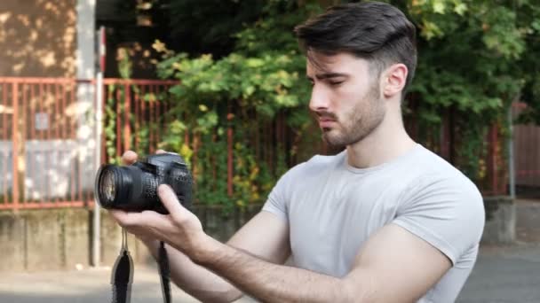 Молодой человек позирует с фотоаппаратом — стоковое видео