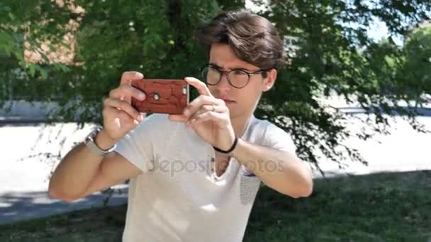 Młody człowiek biorąc Zdjęcia z telefonu komórkowego — Wideo stockowe