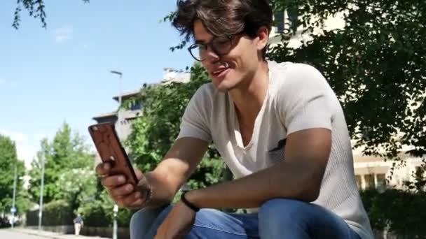 Joven hombre haciendo videochat al aire libre — Vídeos de Stock