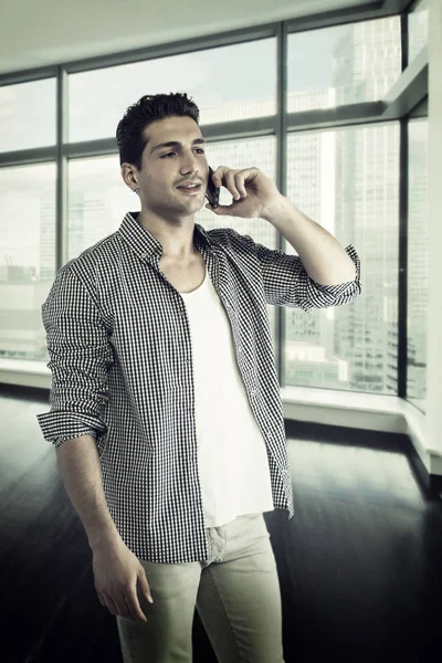 Pohledný mladý muž mluví do mobilního telefonu, s úsměvem — Stock fotografie