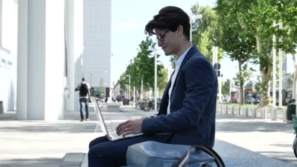 Schöner junger Mann, der im Freien am Computer arbeitet — Stockvideo