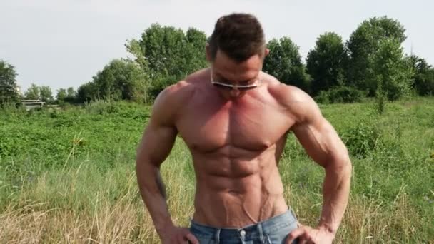 Gespierde bodybuilder man shirtless in gazon — Stockvideo