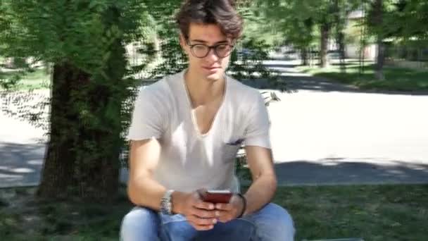 若い男が屋外の携帯電話で入力 — ストック動画