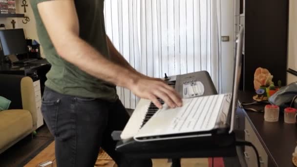 Человек играет в синтезатор с компьютером — стоковое видео