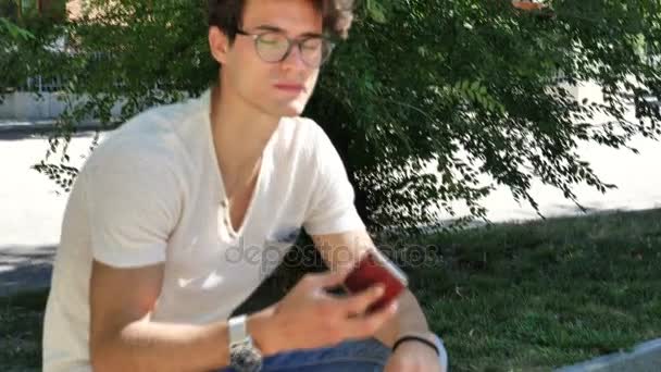 Jeune homme dans le parc de la ville parlant sur téléphone portable — Video