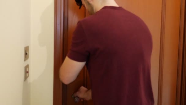 Junger Mann öffnet Tür zur Wohnung — Stockvideo