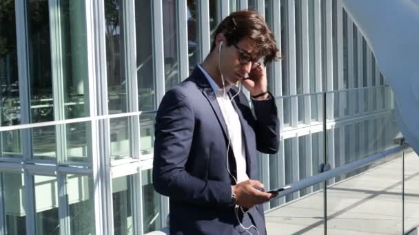 Homem de negócios jovem elegante com fones de ouvido — Vídeo de Stock
