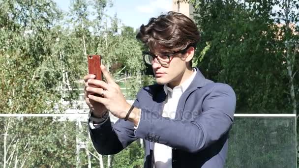 Jeune homme en ville prenant des photos avec un téléphone portable — Video