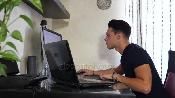 Молодой человек, работающий на компьютере и настольном компьютере — стоковое видео
