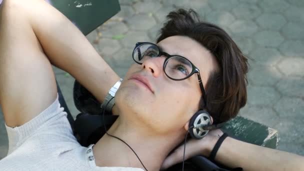 Молодий чоловік слухає музику в парку — стокове відео