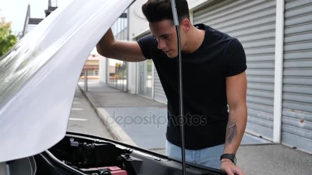 Przystojny młody człowiek próbuje naprawić silnik samochodu — Wideo stockowe