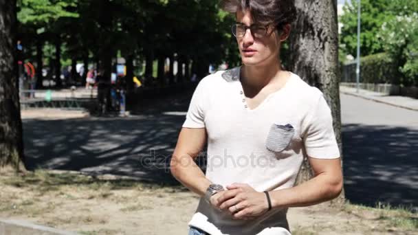 Un joven en el parque esperando a alguien — Vídeos de Stock