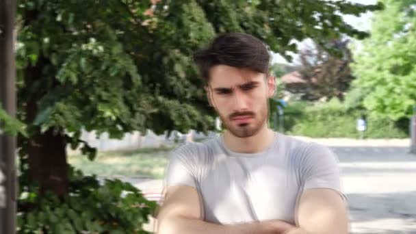 Młody człowiek poważny z ramionami skrzyżowanymi, Na Dworzu — Wideo stockowe