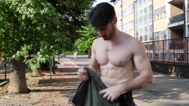 Привабливий м'язистий молодий чоловік одягається — стокове відео
