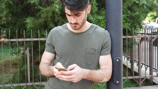 Mladý muž psaní na telefonu na ulici — Stock fotografie