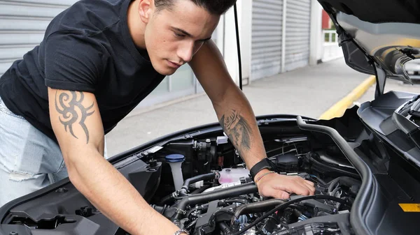Красивий молодий чоловік намагається відремонтувати двигун автомобіля — стокове фото