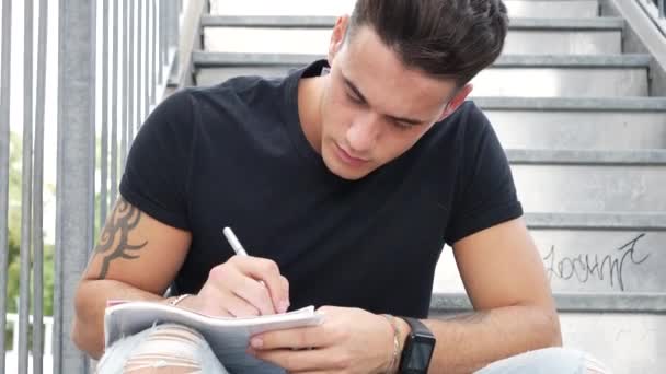 Young man writing on paper sheet with pen — Stock Video