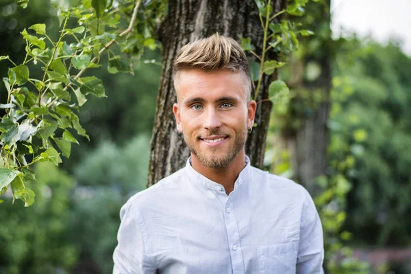 Sad, worried blond young man against tree — Stock Photo, Image