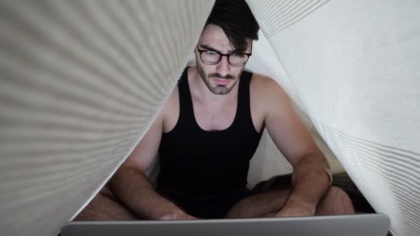 Jongeman doet huiswerk op laptop in de slaapkamer — Stockvideo