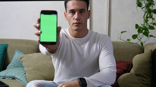 Giovane uomo che mostra i suoi telefoni cellulari schermo verde vuoto — Foto Stock