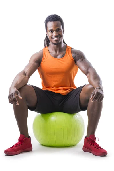 Svalnatý černoch sedí na nafukovací fitness míče — Stock fotografie