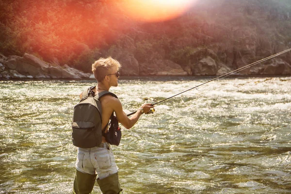 Человек рыбалка с удочкой на реке — стоковое фото
