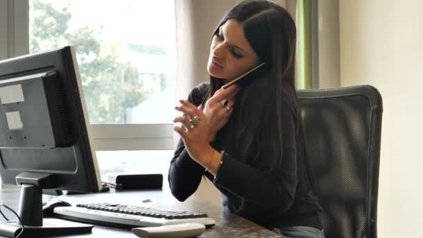 Trabajadora de oficina sentada en el escritorio ocupada con dos teléfonos — Vídeo de stock