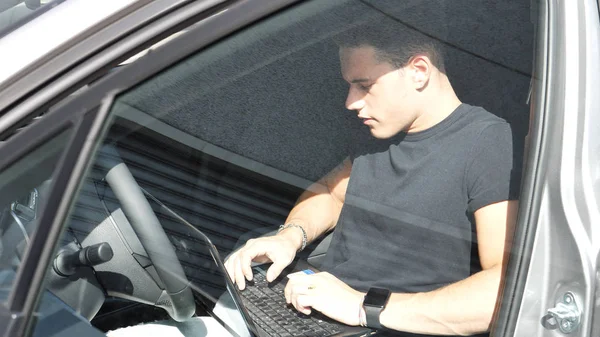 Jovem trabalhando no computador em seu carro — Fotografia de Stock