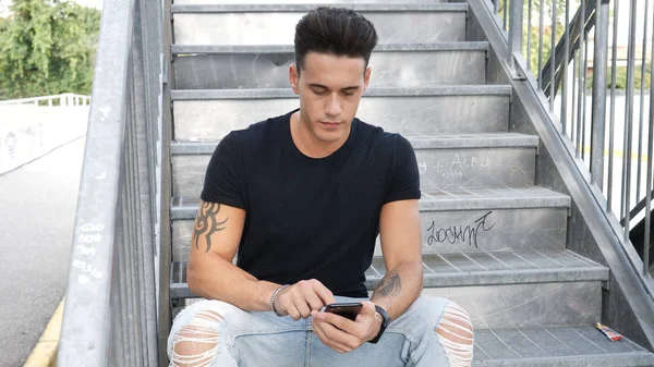 Young man using cellphone outdoors in urban setting — Stock Photo, Image