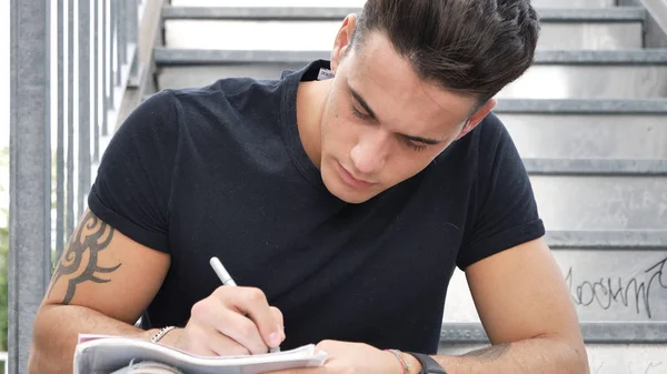 Ung man skriver på papper ark med penna — Stockfoto