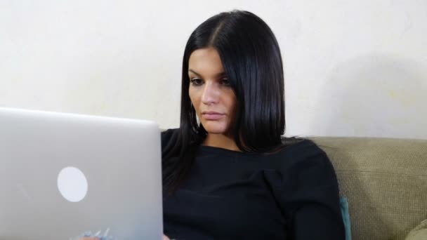 Молода жінка з ноутбуком на дивані Робота над своїм стартап бізнесом — стокове відео
