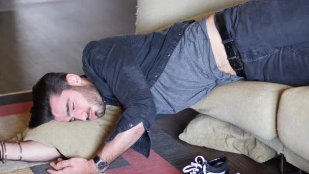 Пьяный мужчина отдыхает на диване с головой на полу — стоковое видео