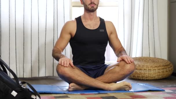 Hombre joven meditando en el suelo de su sala de estar — Vídeos de Stock