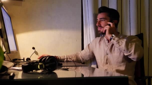 Felice lavoratore seduto alla scrivania a casa occupato al telefono — Video Stock