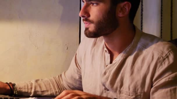 Junger Mann schreibt am Computer auf Papierbogen — Stockvideo