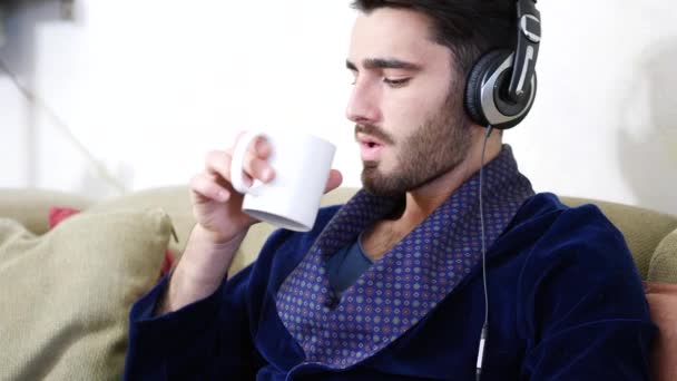 Hombre bebiendo café o té usando auriculares — Vídeos de Stock