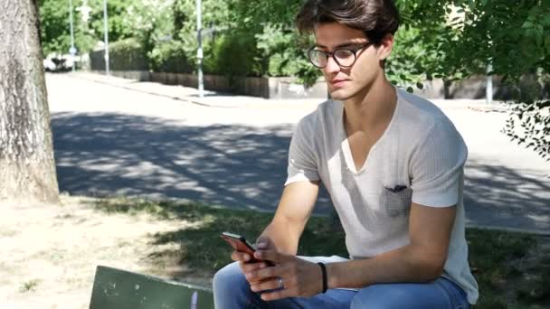 Young man typing on cell phone outdoor — Stock Video