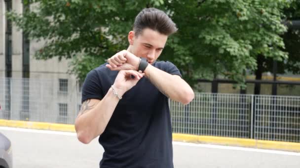 Молодой человек использует умные часы снаружи — стоковое видео