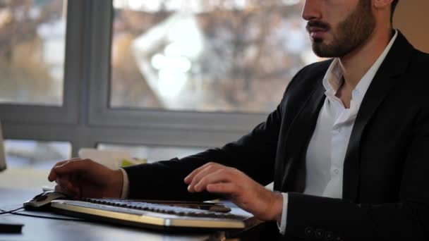 Bonito jovem empresário sentado na mesa no escritório — Vídeo de Stock